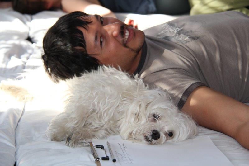 Man smiling with a puppy beside him